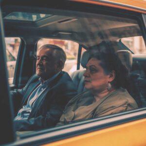 ein älteres Paar sitzt im Wagenfond eines Taxis