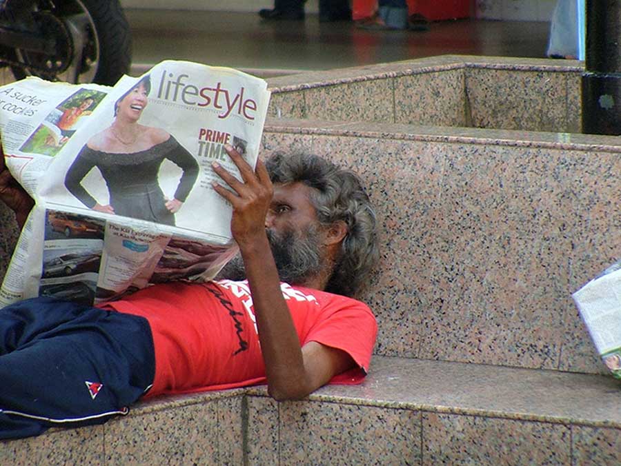 ein obdachloser Mann liest eine Zeitung mit Lifestyle Titel